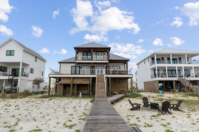 2282 W W Beach Blvd, Gulf Shores, AL 36542 - rear view of house featuring stairs, an outdoor fire pit, a metal roof, and a balcony