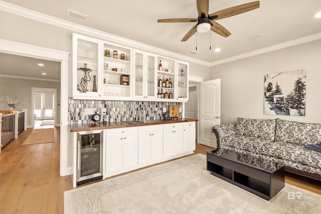2282 W W Beach Blvd, Gulf Shores, AL 36542 - indoor wet bar featuring beverage cooler, decorative backsplash, crown molding, light wood-type flooring, and recessed lighting