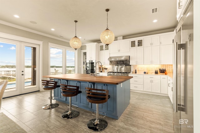 2282 W W Beach Blvd, Gulf Shores, AL 36542 - kitchen featuring wooden counters, exhaust hood, french doors, tasteful backsplash, and white cabinets