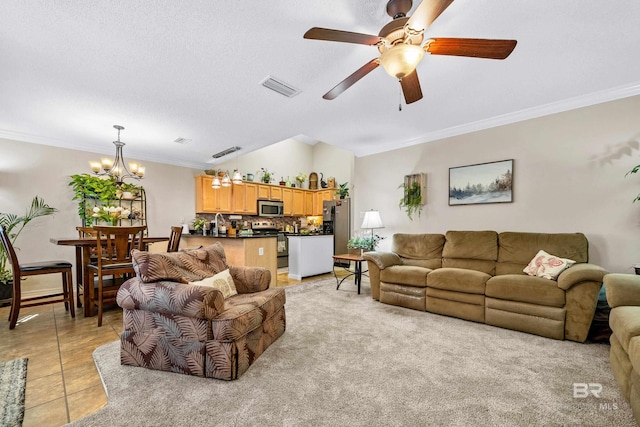 living room featuring light tile patterned floors, ceiling fan with notable chandelier, a textured ceiling, and ornamental molding