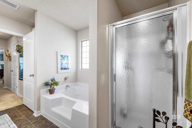 bathroom with a textured ceiling and independent shower and bath