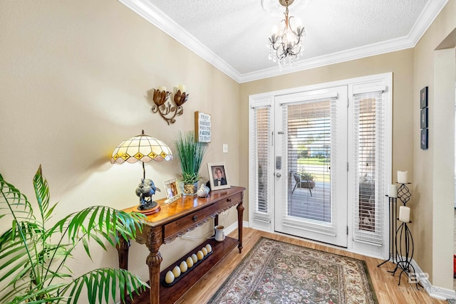 entryway featuring hardwood / wood-style flooring, ornamental molding, a textured ceiling, and an inviting chandelier