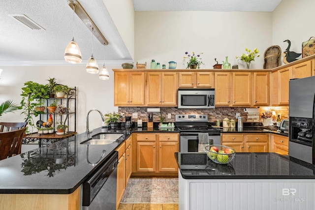 kitchen featuring appliances with stainless steel finishes, hanging light fixtures, dark stone countertops, and sink