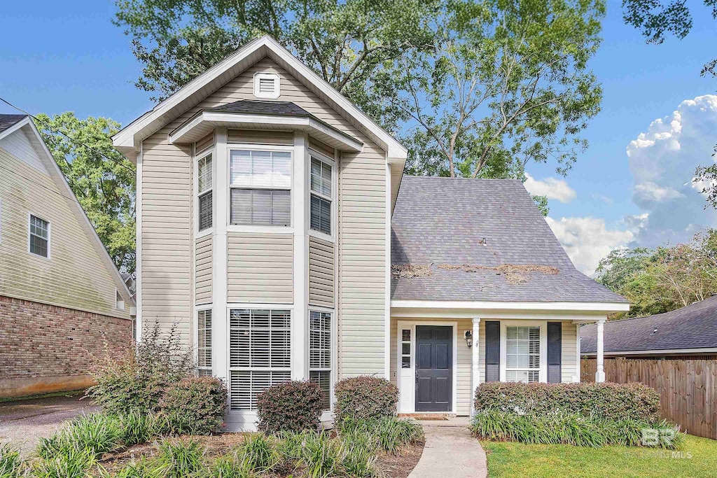 traditional-style home featuring a shingled roof and fence