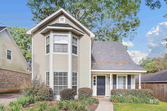 traditional-style home featuring a shingled roof and fence