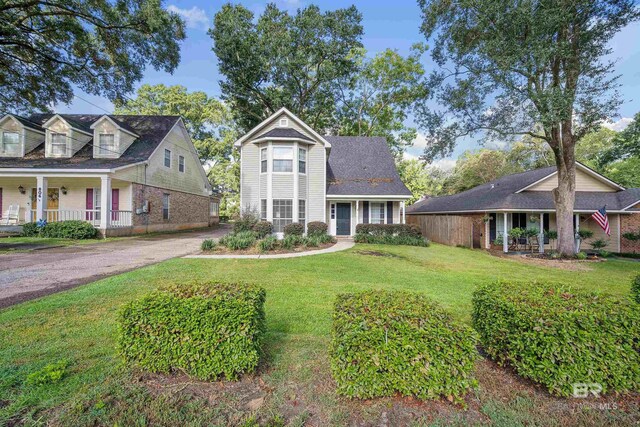 cape cod house featuring covered porch and a front yard