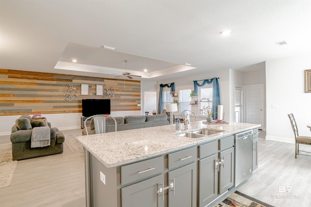kitchen featuring stainless steel dishwasher, baseboards, a raised ceiling, a sink, and gray cabinetry