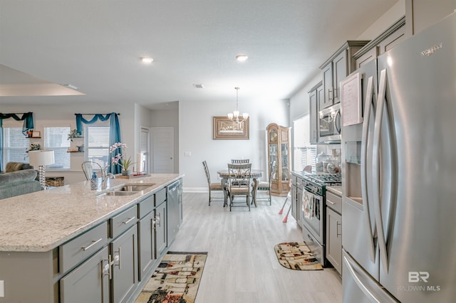 kitchen featuring gray cabinetry, stainless steel appliances, a sink, and open floor plan