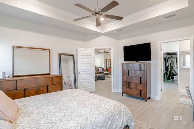 bedroom featuring visible vents, light wood-type flooring, a closet, a spacious closet, and ornamental molding
