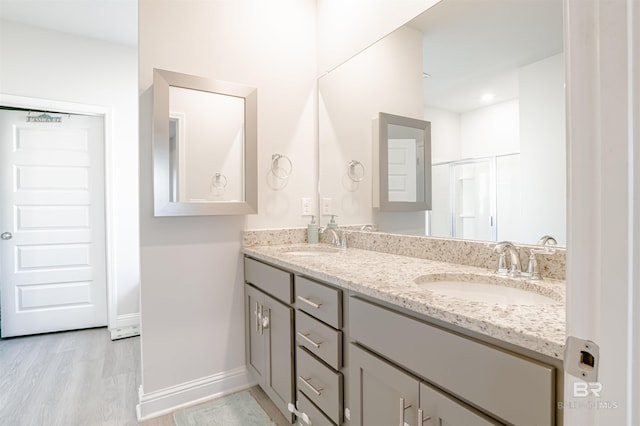 full bathroom featuring an enclosed shower, double vanity, a sink, and wood finished floors