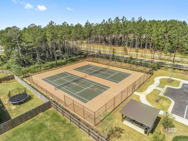 view of sport court featuring fence, a trampoline, and a lawn