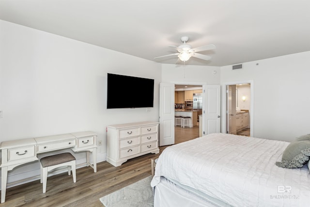 bedroom featuring visible vents, connected bathroom, ceiling fan, wood finished floors, and stainless steel built in refrigerator