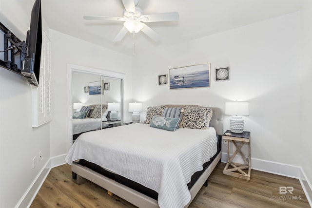 bedroom with a closet, wood finished floors, a ceiling fan, and baseboards