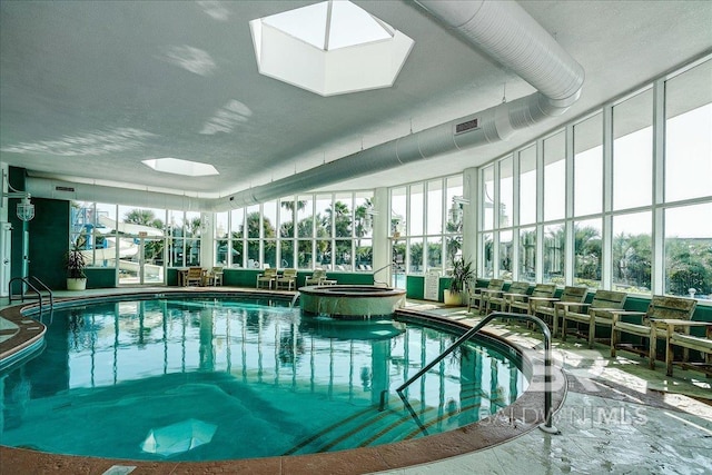 view of pool with a skylight and a pool with connected hot tub