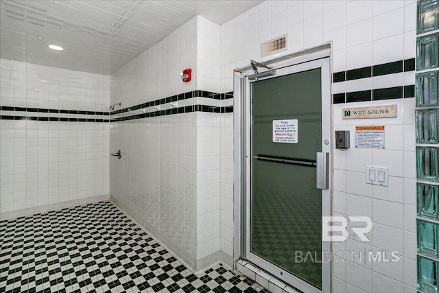 full bath featuring a shower stall, visible vents, and tile walls