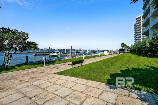 view of community with a dock, a water view, and a lawn