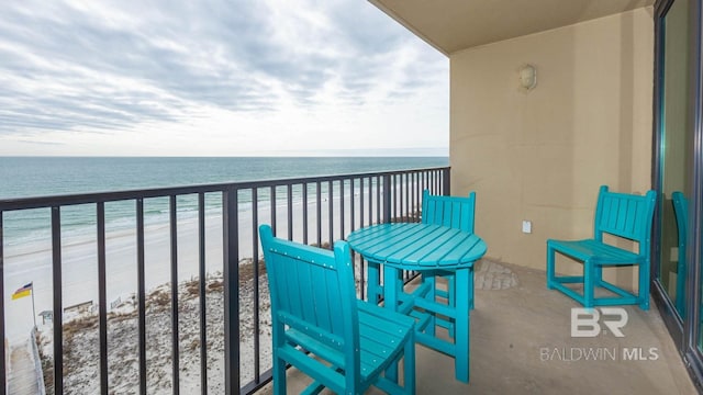 balcony featuring a view of the beach and a water view