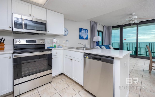 kitchen featuring a textured ceiling, kitchen peninsula, white cabinetry, and stainless steel appliances