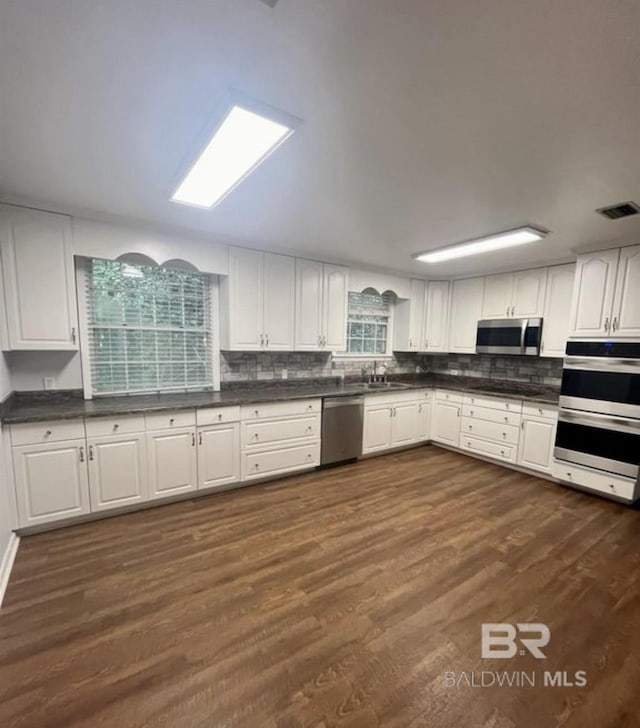 kitchen with white cabinetry, stainless steel appliances, dark hardwood / wood-style flooring, and sink