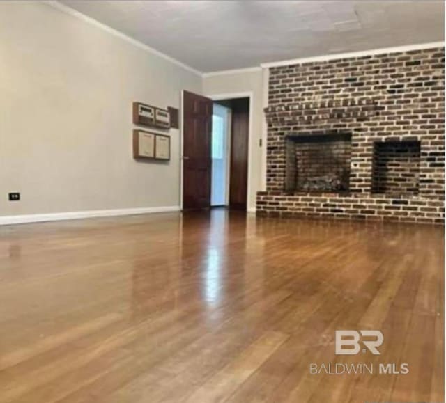 unfurnished living room with hardwood / wood-style flooring and crown molding