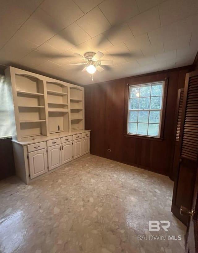 interior space featuring ceiling fan and wood walls