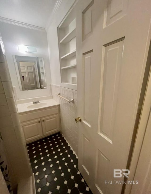 bathroom featuring built in shelves, ornamental molding, tile walls, and vanity