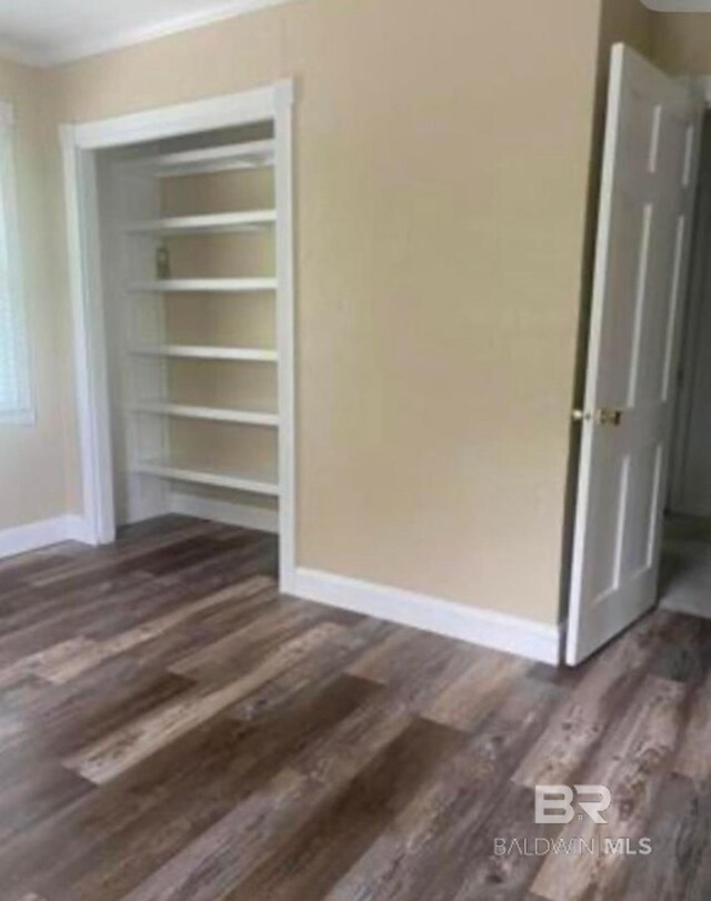 spare room with built in shelves and dark wood-type flooring