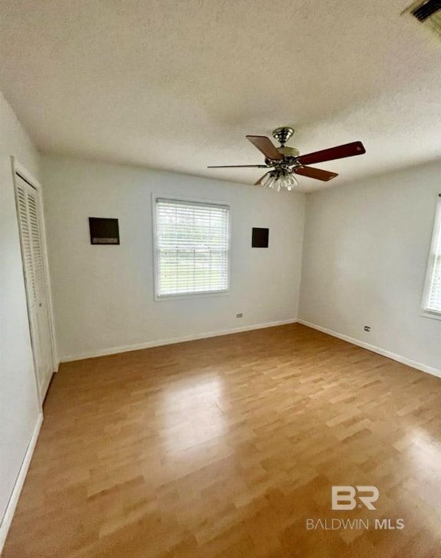 unfurnished room with a textured ceiling, light hardwood / wood-style flooring, and ceiling fan