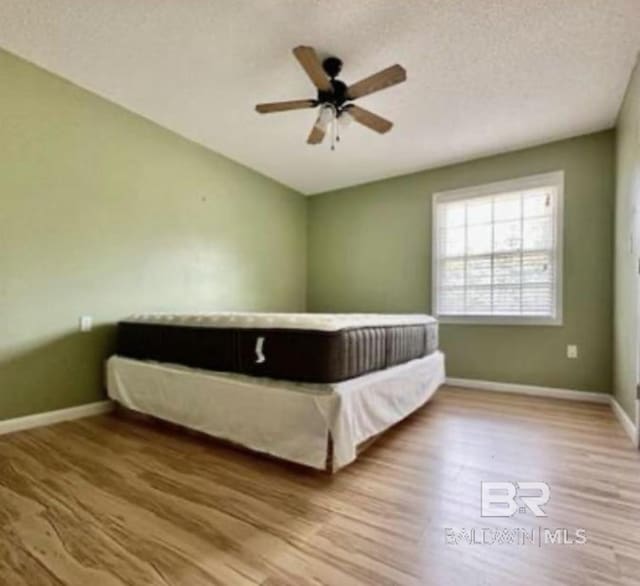 unfurnished bedroom featuring ceiling fan, hardwood / wood-style floors, and a textured ceiling