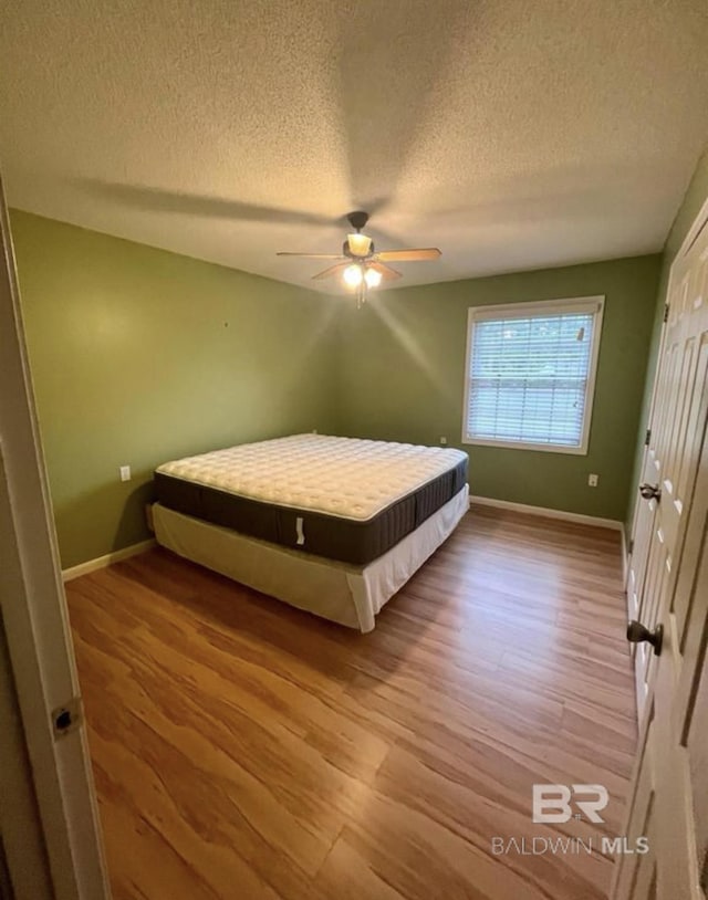 bedroom with a textured ceiling, ceiling fan, and light hardwood / wood-style floors