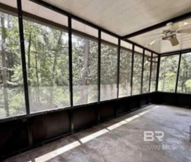 unfurnished sunroom featuring ceiling fan and a wealth of natural light