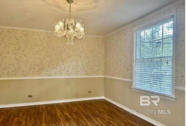 spare room with crown molding, dark wood-type flooring, and a chandelier