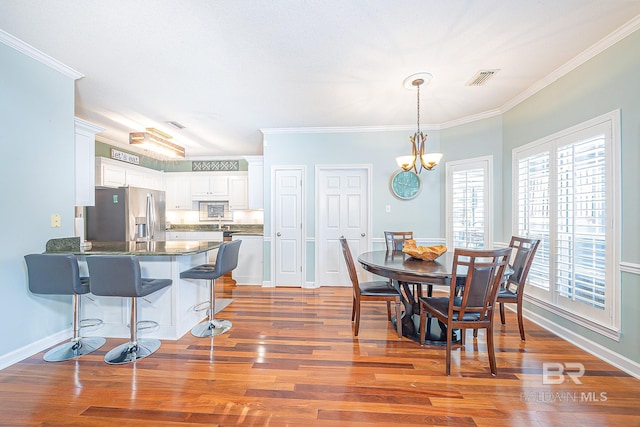 dining area with ornamental molding, a notable chandelier, and dark hardwood / wood-style floors