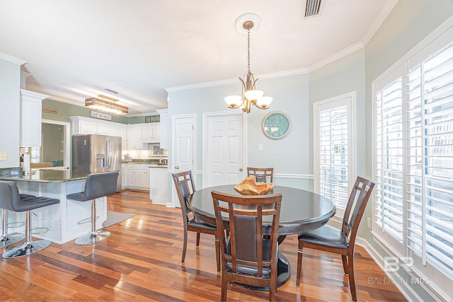 dining space featuring an inviting chandelier, crown molding, and hardwood / wood-style flooring