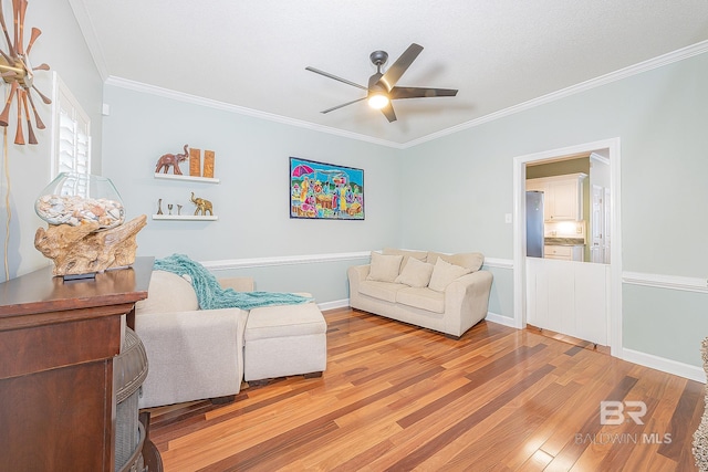 living room featuring ceiling fan, ornamental molding, and light hardwood / wood-style flooring