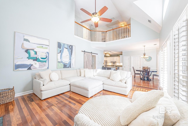 living room featuring high vaulted ceiling, hardwood / wood-style floors, ceiling fan, and a barn door