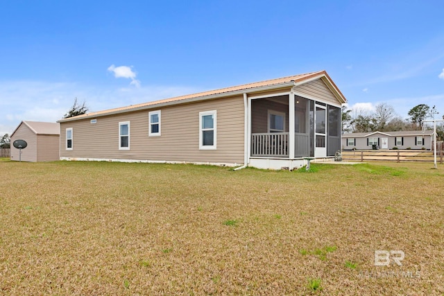 rear view of property with a sunroom, fence, metal roof, and a lawn