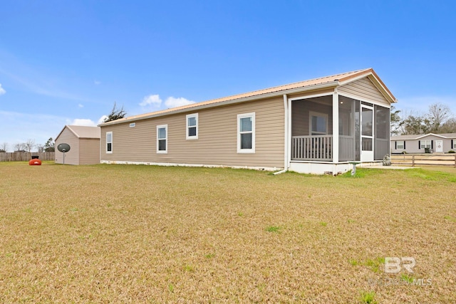 back of property with metal roof, a lawn, and a sunroom