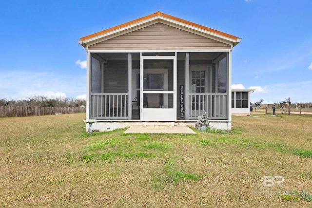 view of front facade with a front lawn, fence, and a sunroom