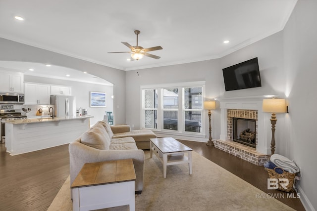 living room featuring crown molding, a fireplace, dark hardwood / wood-style flooring, and ceiling fan