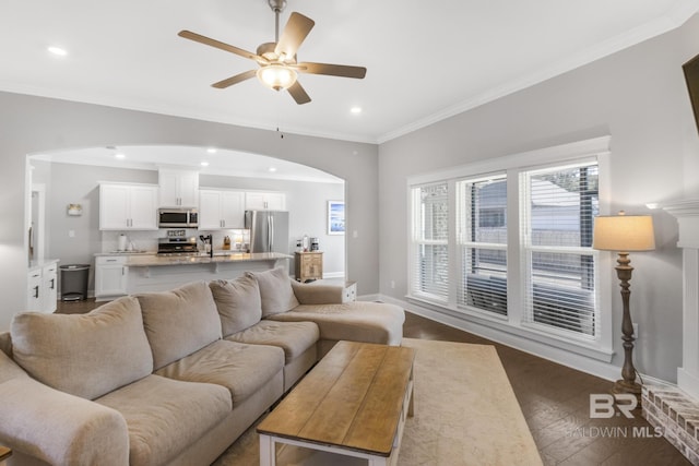 living room with crown molding, dark wood-type flooring, and ceiling fan