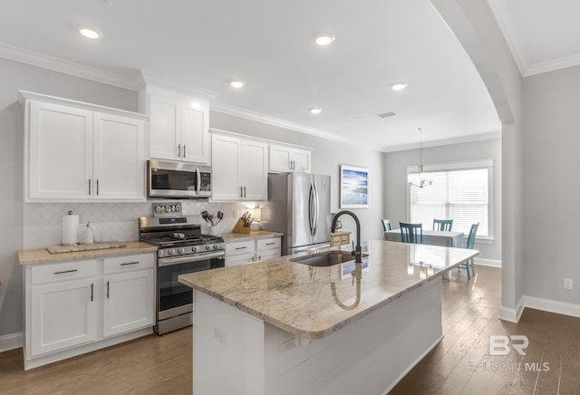 kitchen with an island with sink, stainless steel appliances, sink, and white cabinets