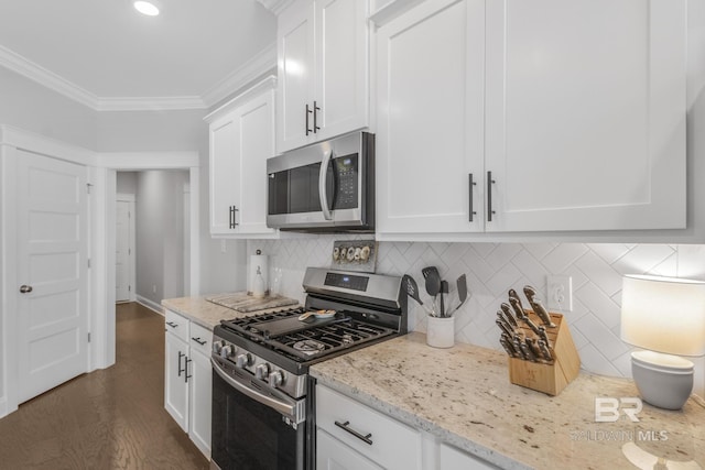 kitchen featuring crown molding, light stone counters, white cabinets, stainless steel appliances, and backsplash