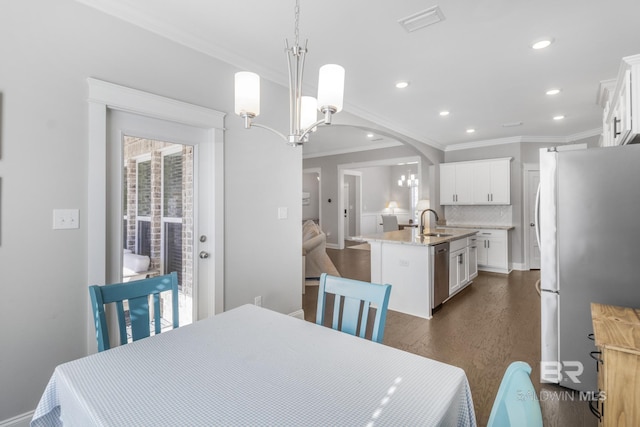 dining area with an inviting chandelier, sink, dark hardwood / wood-style flooring, and ornamental molding