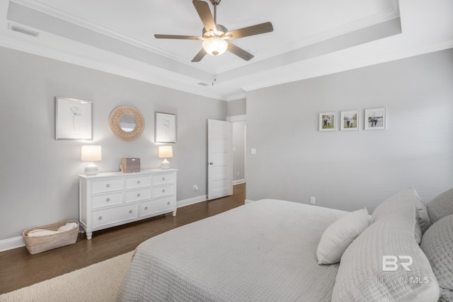 bedroom with dark wood-type flooring, ceiling fan, ornamental molding, and a raised ceiling