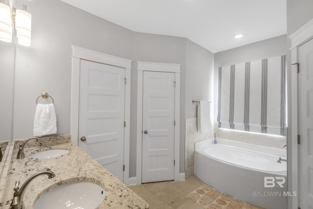 bathroom with tile patterned flooring, vanity, and a bath