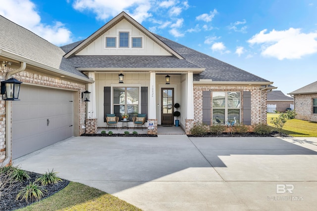 view of front of home with a porch, an attached garage, a shingled roof, concrete driveway, and brick siding