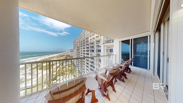 balcony with a water view and a view of the beach