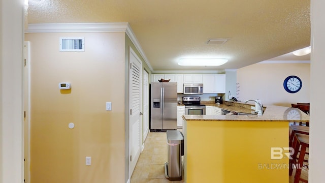 kitchen with kitchen peninsula, a textured ceiling, stainless steel appliances, white cabinetry, and a breakfast bar area