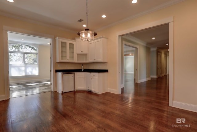 kitchen featuring white dishwasher, dark wood-type flooring, dark countertops, glass insert cabinets, and crown molding